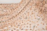 A fine beaded embroidery fabric, with a vertical stripe pattern made of tiny floral and starburst motifs in champagne-pink and pewter.
