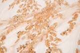 A hand-beaded embroidery fabric, with a pattern of fern-like leaves in a warm, copper-gold color palette.