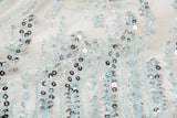 A fine beaded embroidery fabric, with a vertical dashed-line pattern resembling rain, in shades of ice blue and silver.