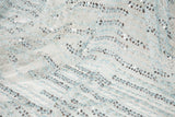 A fine beaded embroidery fabric, with a vertical dashed-line pattern resembling rain, in shades of ice blue and silver.