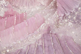 A 3D embroidery fabric with ribbon scallop motifs in a pink and lilac gradient.
