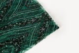 An emerald green Art Deco beaded fabric, with concentric, eye-shaped patterns in black sequins and beads.