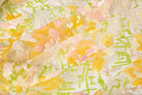 A sequin embroidery fabric on white mesh with yellow-pink florals over green geometric patterns.