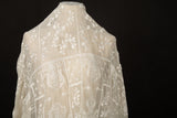 An ivory-white flat embroidery organza fabric, with a horizontal striped pattern of floral friezes and vines.