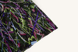 An abstract embroidery fabric on black tulle, with a graffiti-like pattern of lines made from neon green, pink, and purple sequins and thread