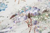 An embroidery fabric on ivory mesh, with a painterly pattern of water lilies in a blue and purple palette.