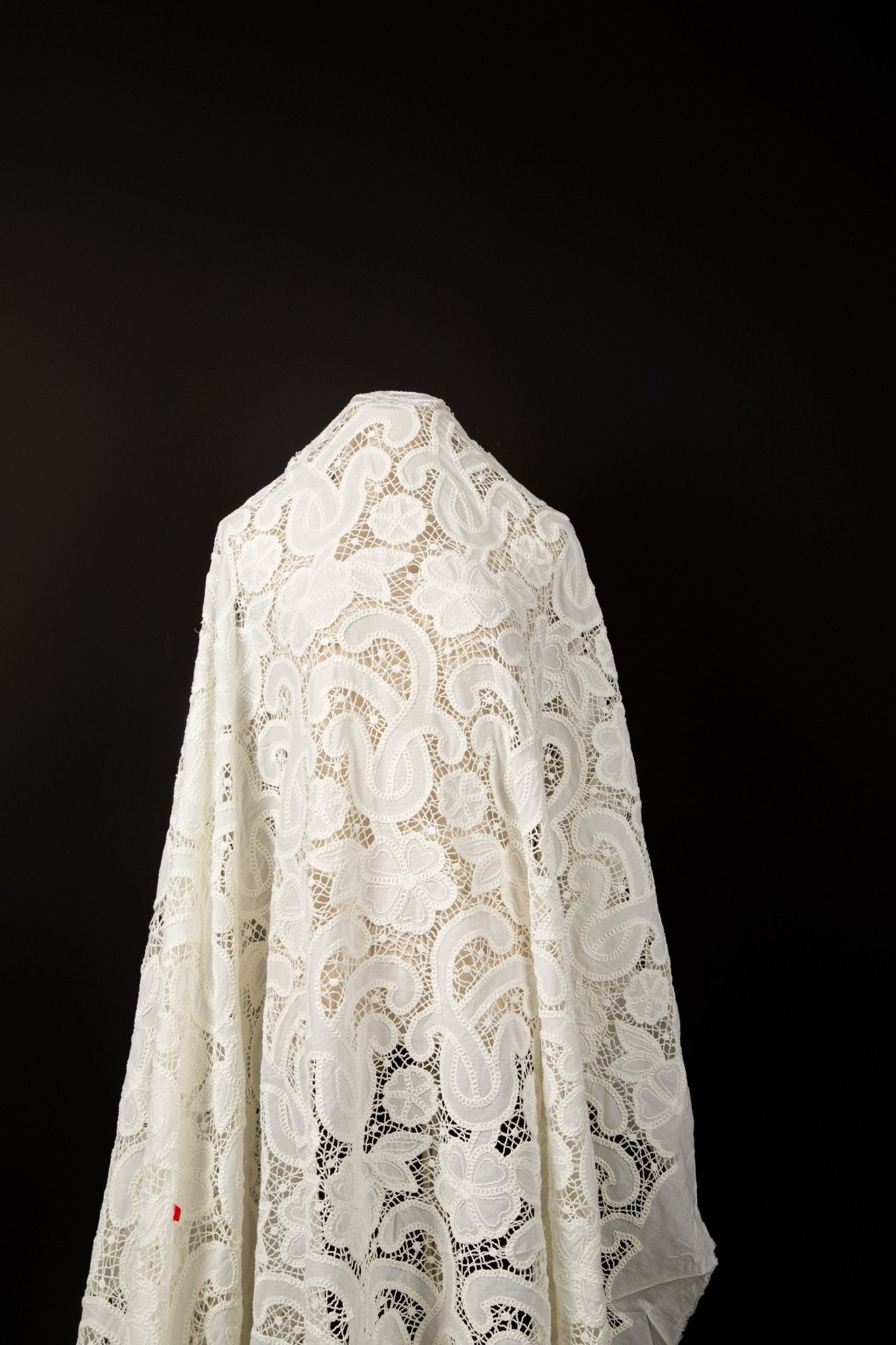 A white laser-cut lace fabric, featuring large-scale, swirling paisley and floral motifs.