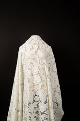 A white laser-cut lace fabric, featuring large-scale, swirling paisley and floral motifs.