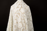 A white laser-cut lace fabric, featuring large-scale, swirling paisley and floral motifs.