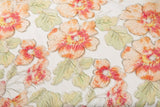 A luxurious floral fabric made with ribbon embroidery, featuring coral-colored flowers and green leaves.