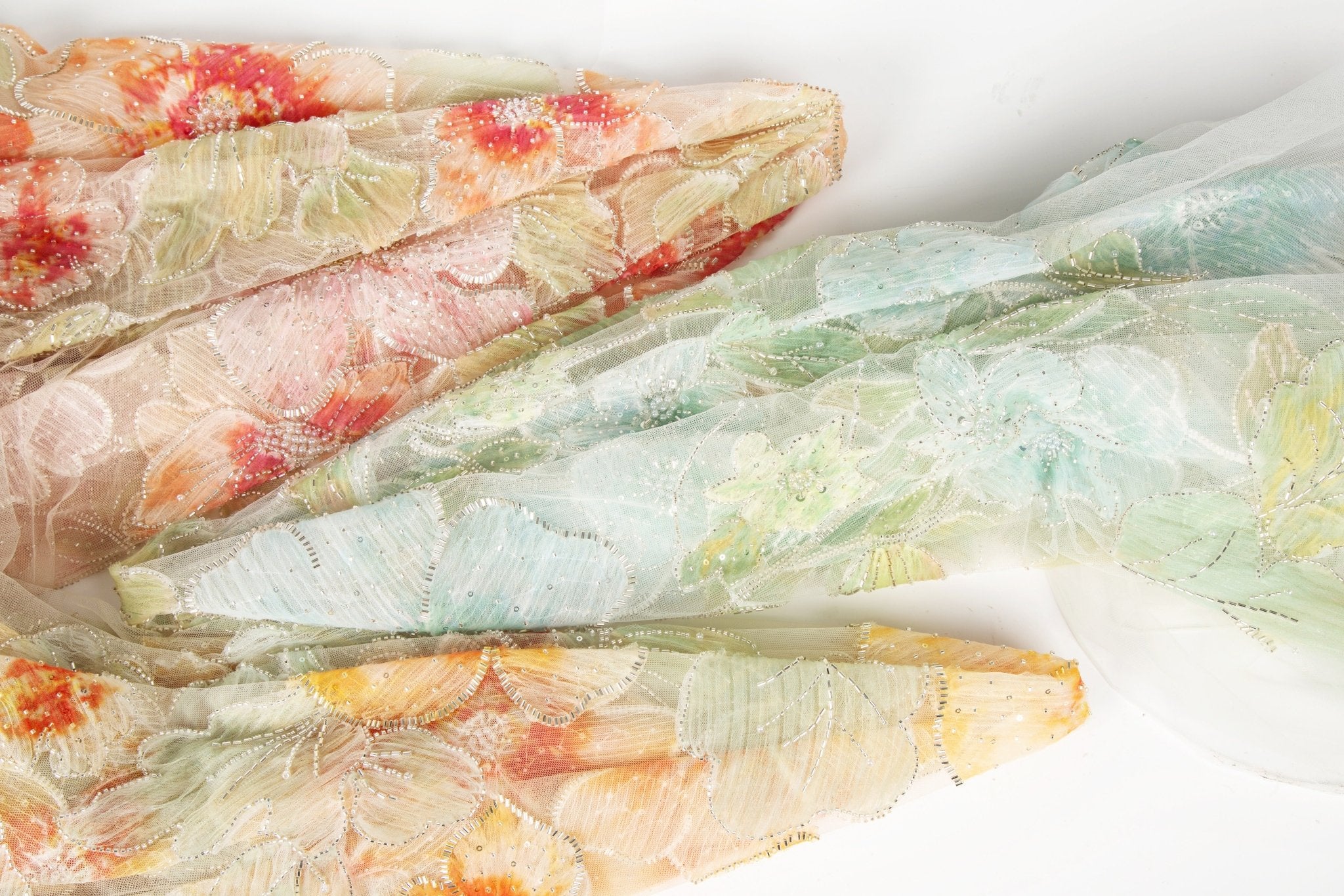 A luxurious fabric made with ribbon embroidery, featuring a large-scale leaf pattern in shades of mint green and blue.
   A luxurious floral fabric made with ribbon embroidery, featuring coral-colored flowers and green leaves.
   A luxurious fabric made with ribbon embroidery, featuring large-scale, yellow and orange flowers with green leaves.