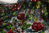 A sequin floral embroidery fabric on a black base, with red and green motifs.
