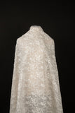 An ivory-white flat embroidery organza fabric, with a graceful, scalloped or arched garland pattern made of small flowers.