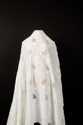 A white laser-cut embroidery fabric, with a pattern of geometric cut-out squares and white floral embroidery.