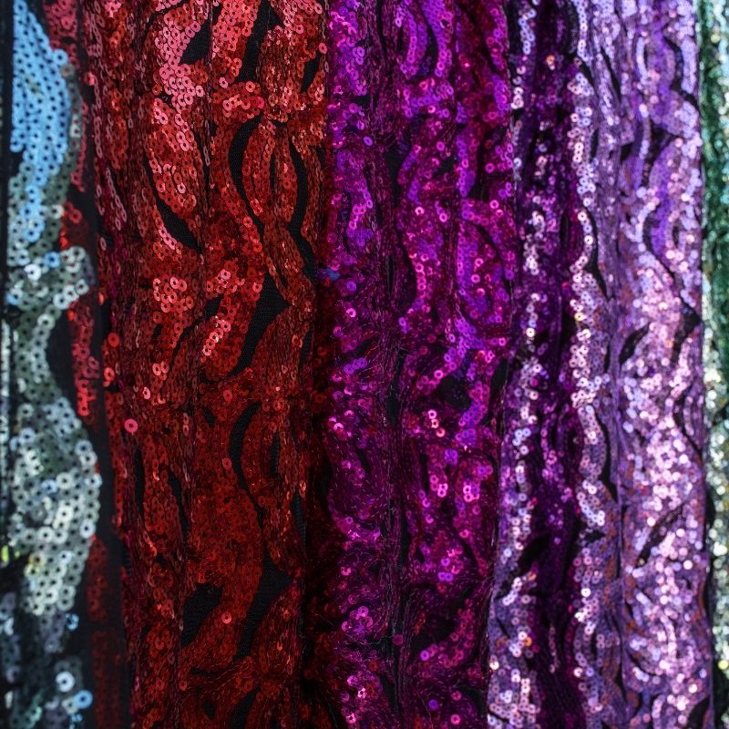 A collection of striking red sequin fabric, highly saturated blue fabric, and custom pink fabrics displayed alongside a Pantone color swatch for exact matching.