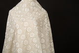 An ivory-white flat embroidery organza fabric, with a repeating, damask-style floral pattern.
