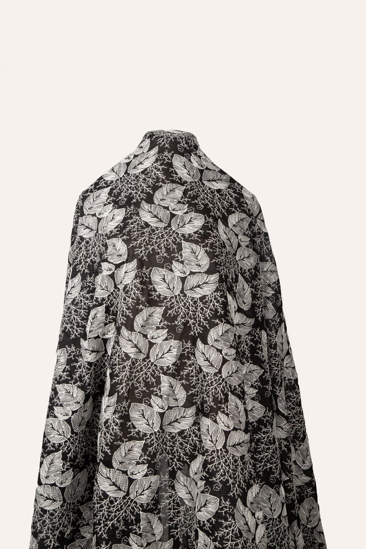 A black and white embroidered cotton fabric, with a stylized pattern of large leaves and coral, resembling a woodcut print.
