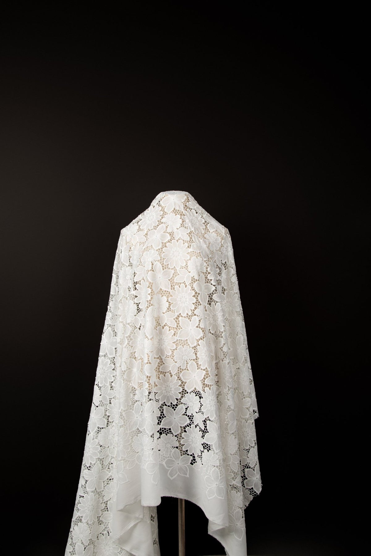 A white laser-cut lace fabric, featuring an all-over pattern of stylized daisies.