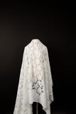 A white laser-cut lace fabric, featuring an all-over pattern of stylized daisies.