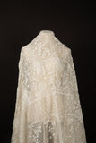 An ivory-white flat embroidery organza fabric, with a horizontal striped pattern of floral friezes and vines.
