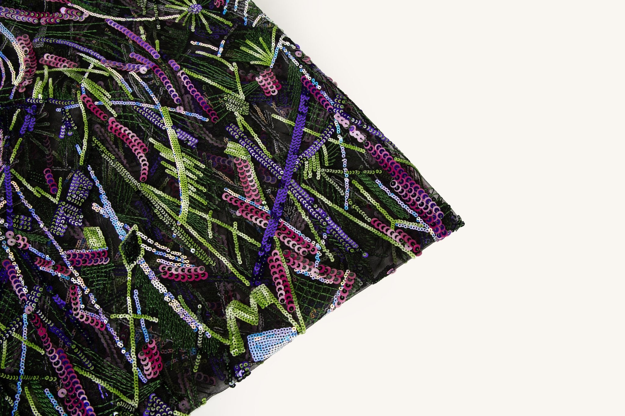  An abstract embroidery fabric on black tulle, with a graffiti-like pattern of lines made from neon green, pink, and purple sequins and thread