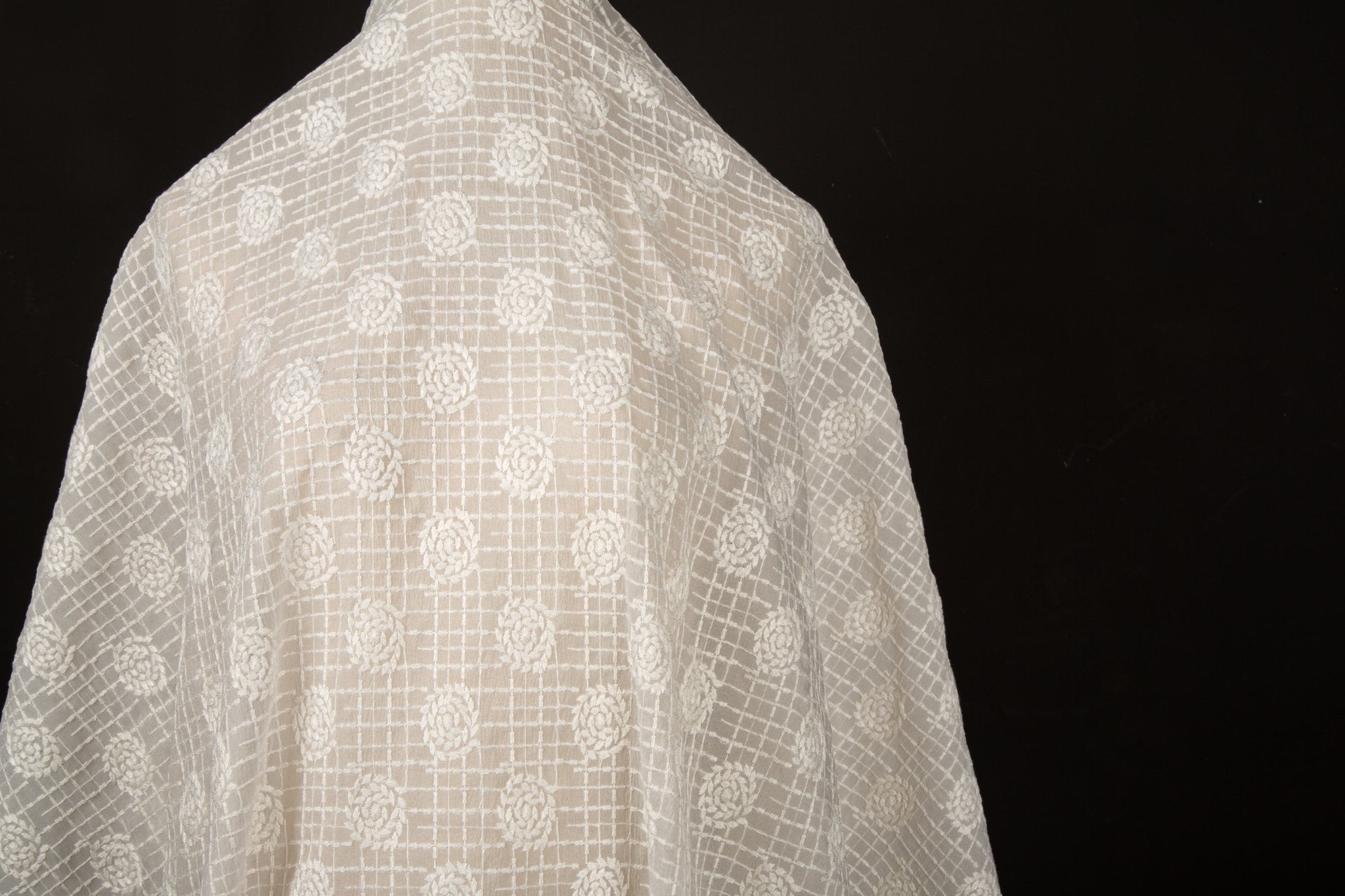 An ivory-white flat embroidery organza fabric, with a pattern combining a grid and floral-filled polka dots.
