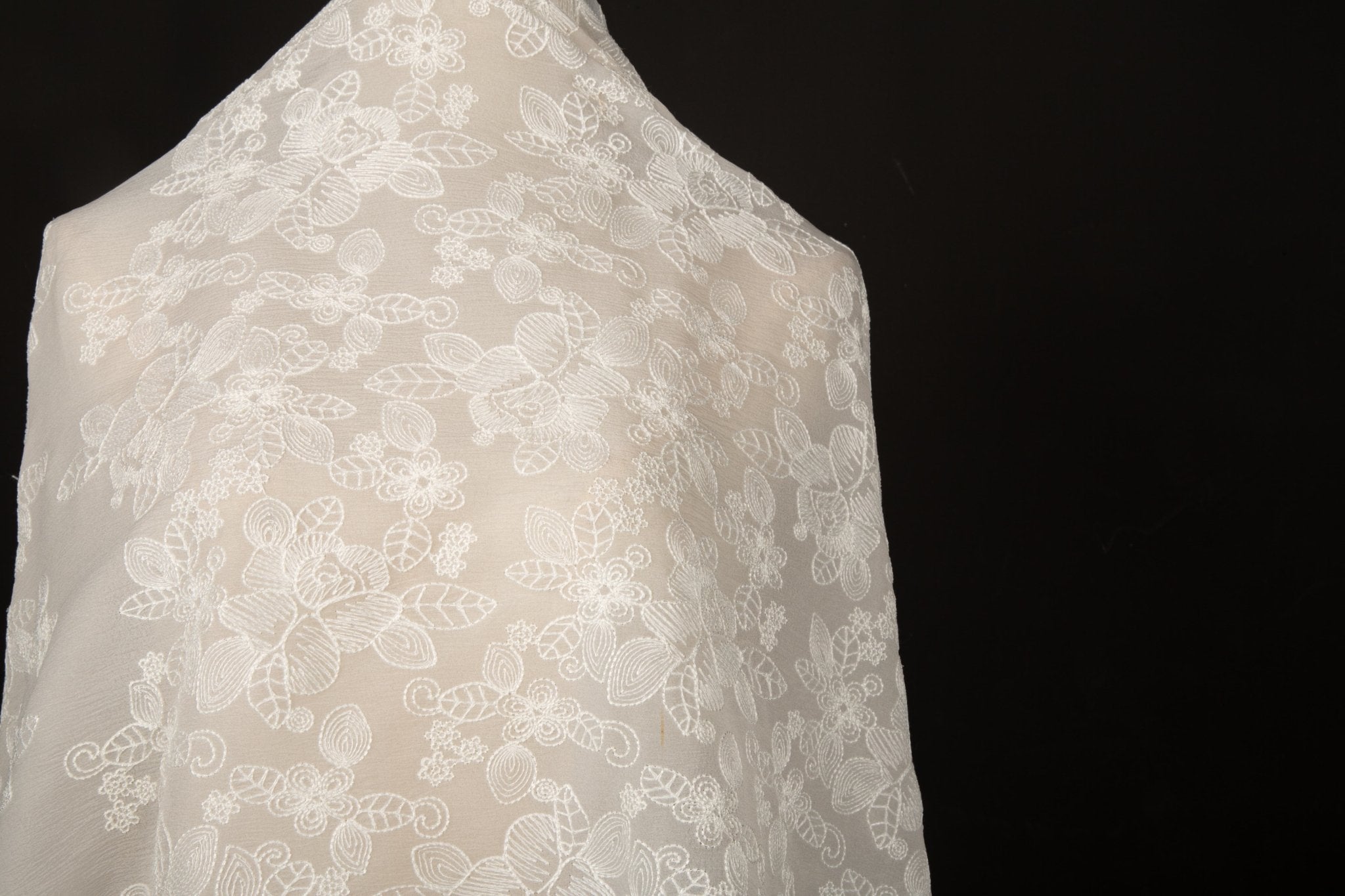 An ivory-white flat embroidery organza fabric, with an abstract, continuous-line floral pattern resembling line art.
