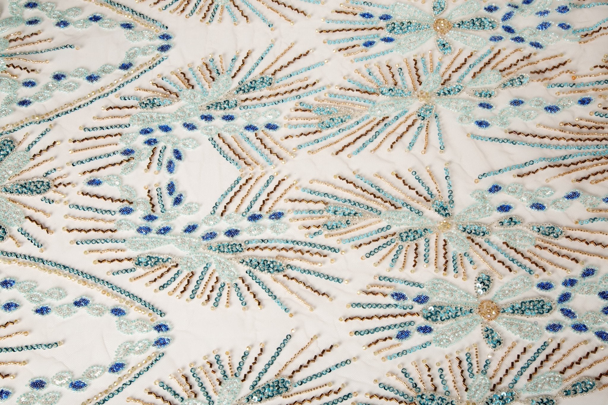 An Art Deco style beaded fabric, with a radiating fireworks or sunburst pattern in aqua, royal blue, and bronze.
