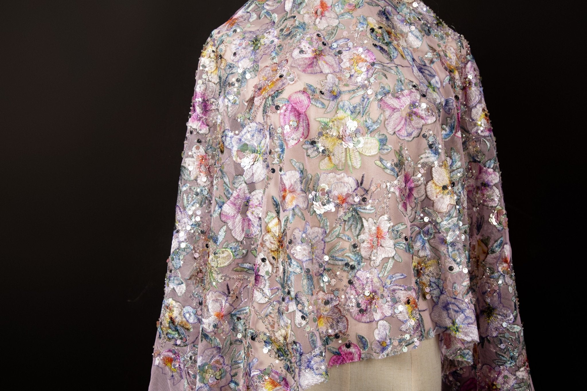 A dense, painterly floral sequin and thread embroidery fabric in a cool palette of purples and blues.
