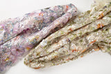    A dense, painterly floral sequin and thread embroidery fabric in a warm palette of greens and oranges.
    A dense, painterly floral sequin and thread embroidery fabric in a cool palette of purples and blues.
