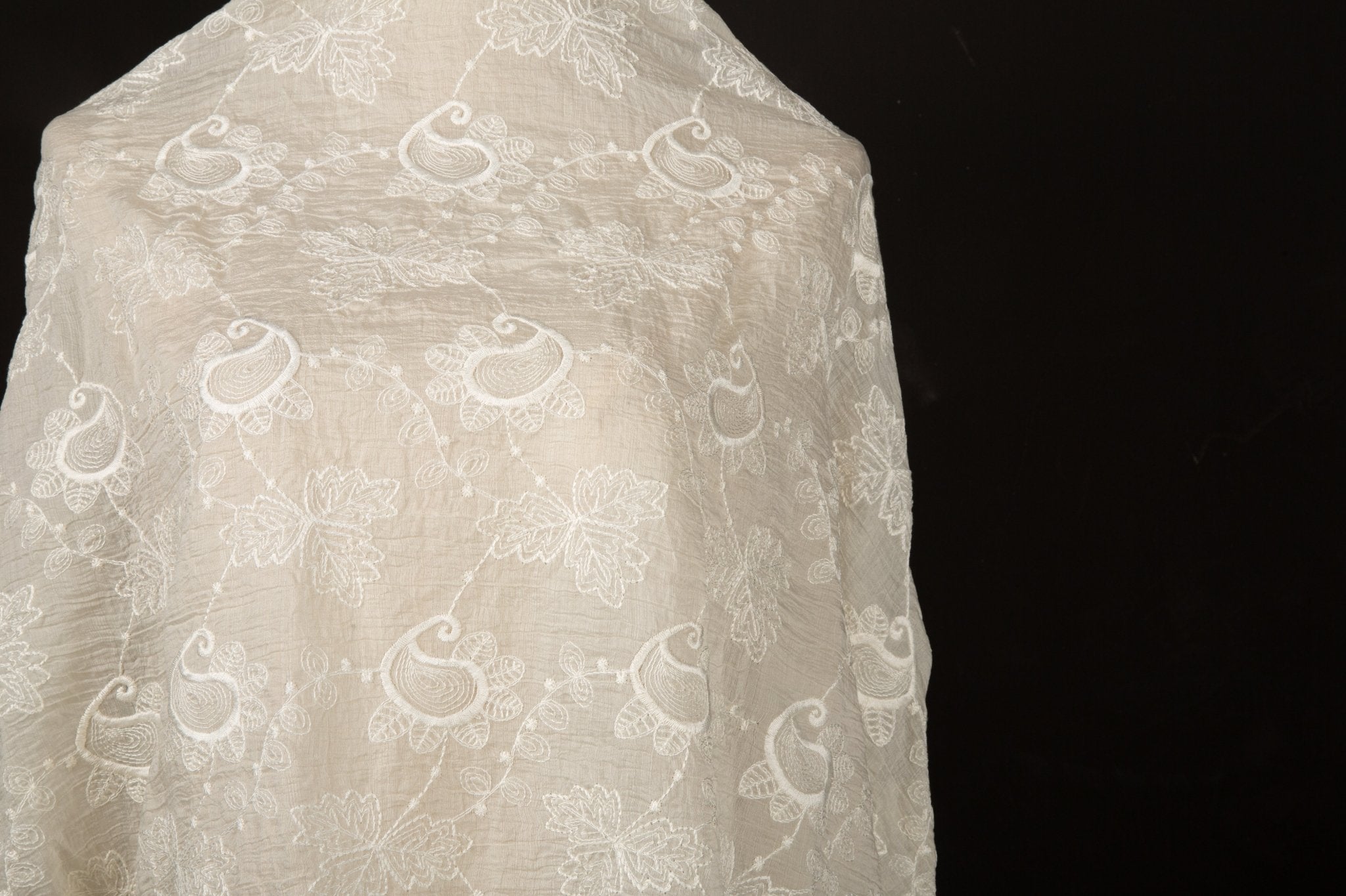An ivory-white flat embroidery cotton fabric, with a repeating, classic paisley pattern.
