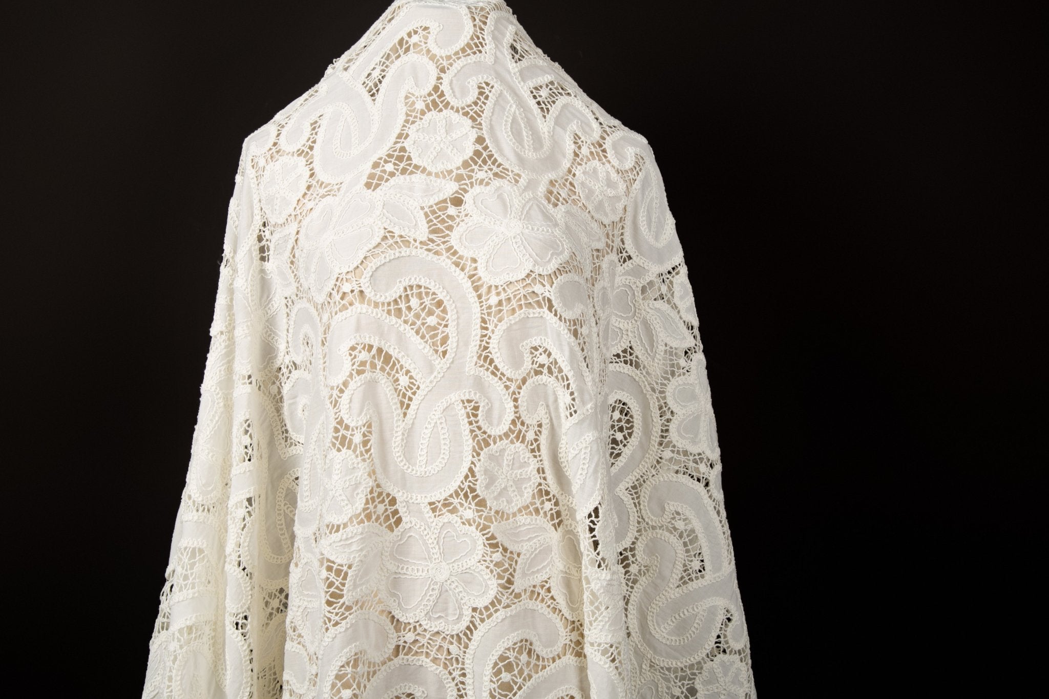  A white laser-cut lace fabric, featuring large-scale, swirling paisley and floral motifs.