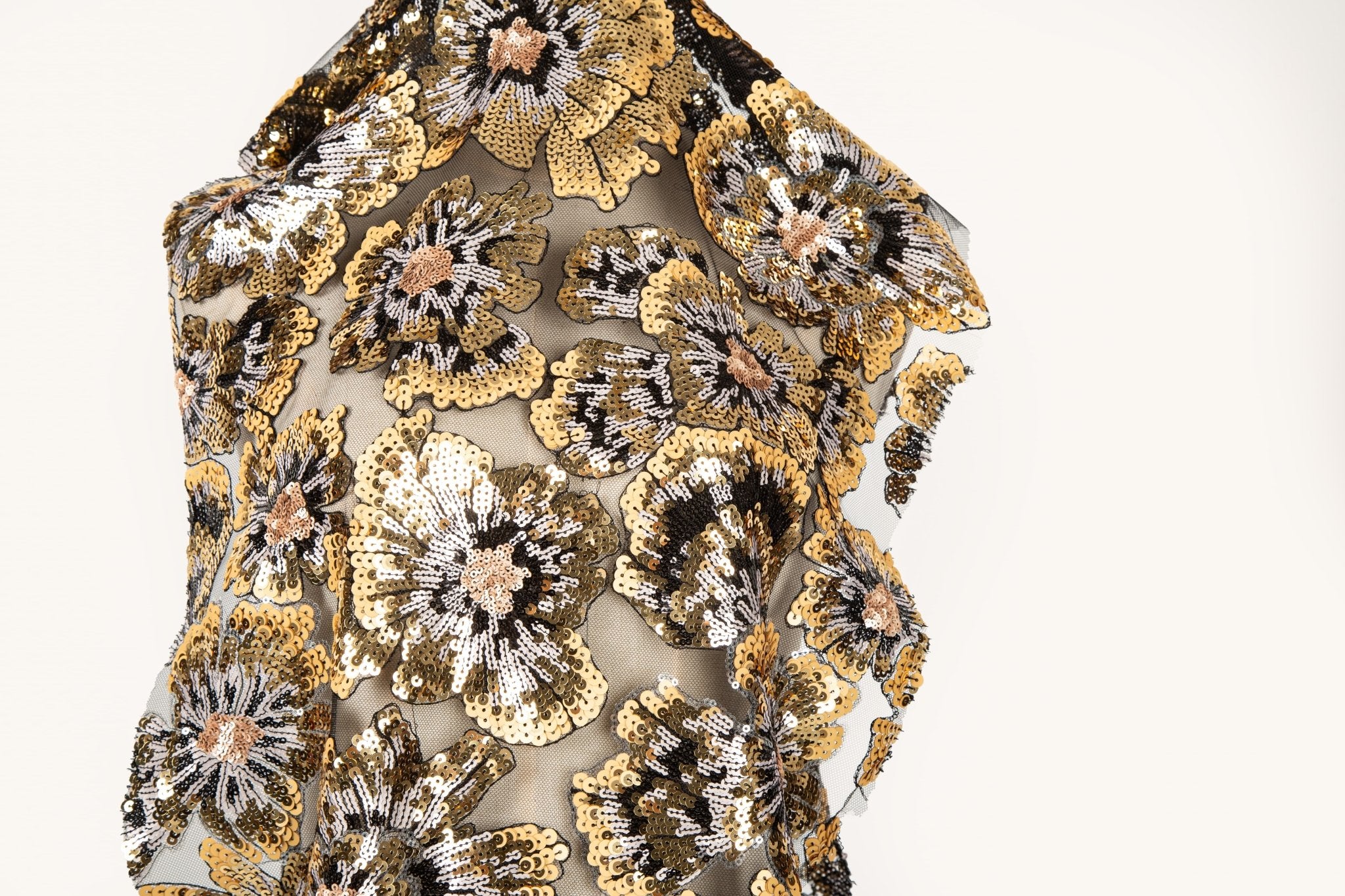 A large floral sequin embroidery fabric on a nude base, with gold, black, and white motifs.

