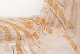 A hand-beaded embroidery fabric, with a vertical, wavy pattern of laurel leaves in rose gold, pink, and green.
