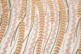 A hand-beaded embroidery fabric, with a vertical, wavy pattern of laurel leaves in rose gold, pink, and green.
