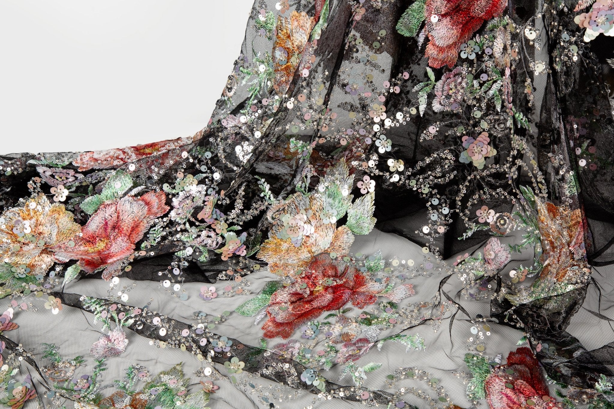 A painterly floral sequin and thread embroidery fabric on a black mesh base with richly colored flowers.
