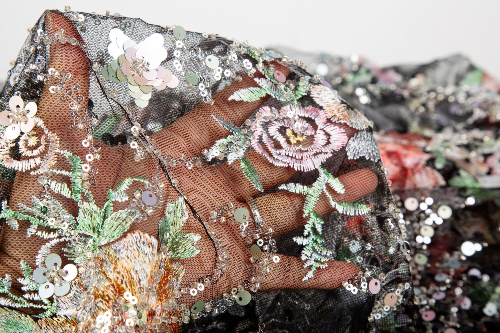 A painterly floral sequin and thread embroidery fabric on a black mesh base with richly colored flowers.
