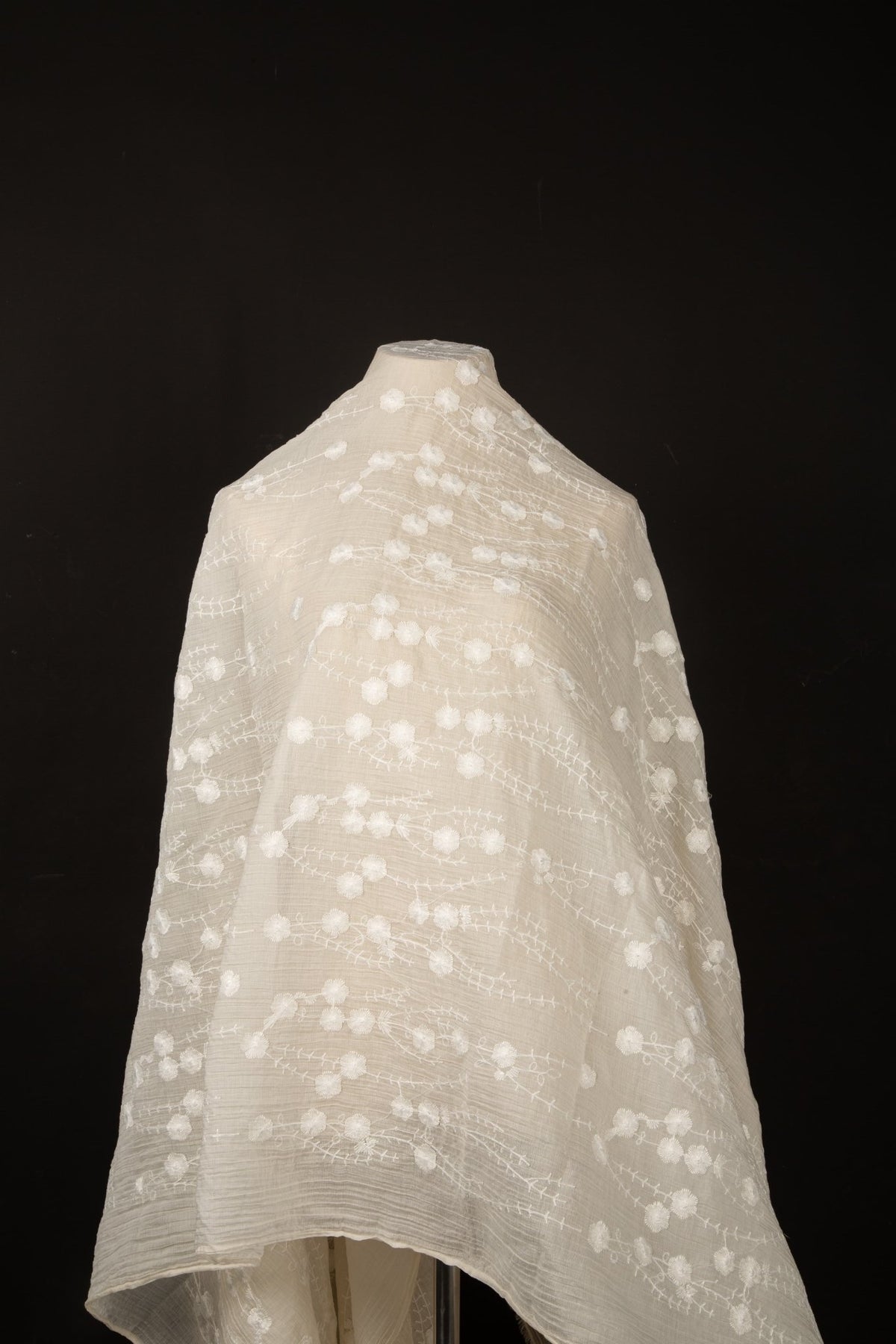 An ivory-white crinkle cotton embroidery fabric, with a horizontal wavy pattern of polka dots and thorny vine lines.
