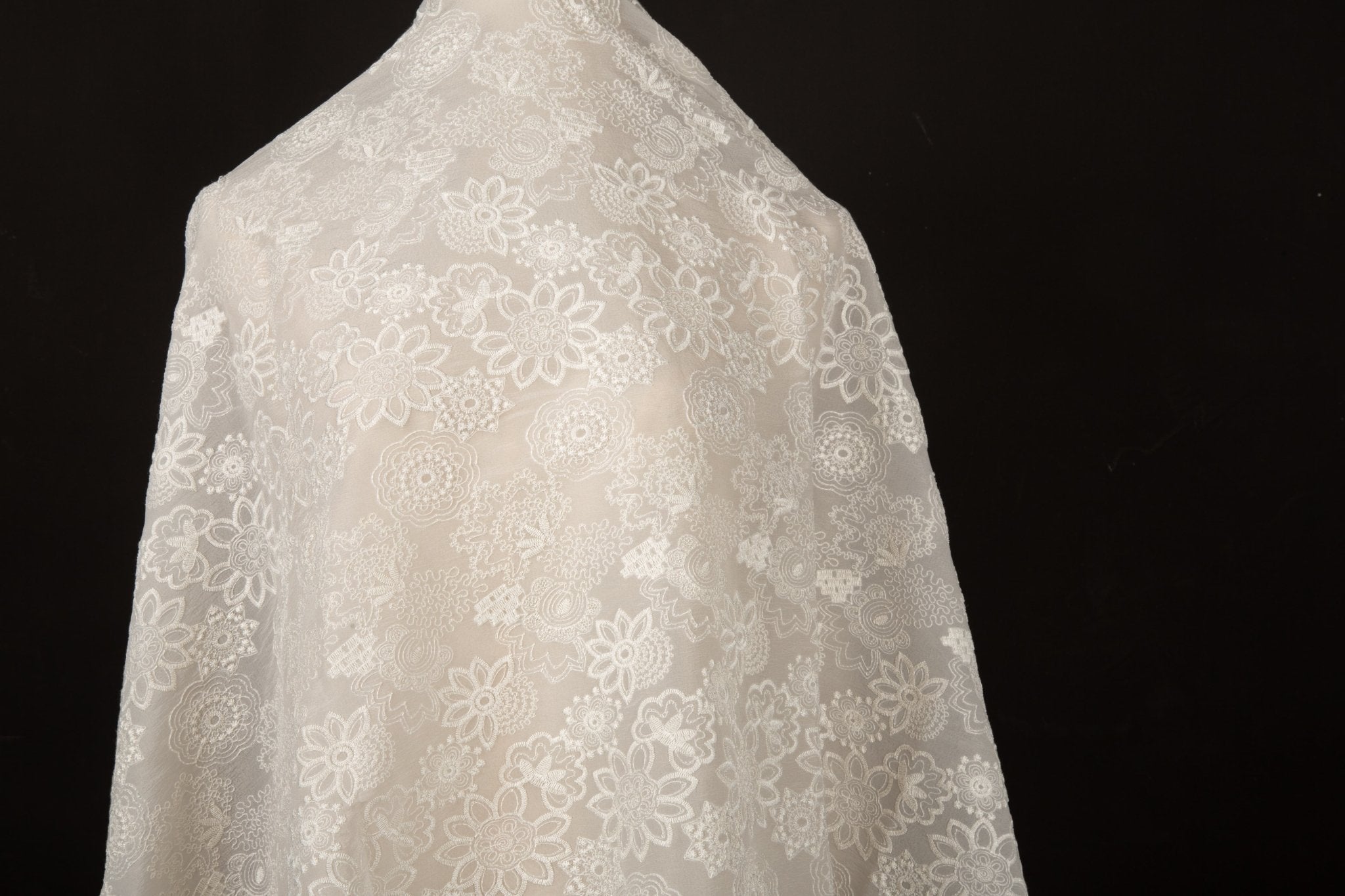 A lightweight, ivory-white flat embroidery organza fabric, with a variety of stylized, outline-floral motifs.

