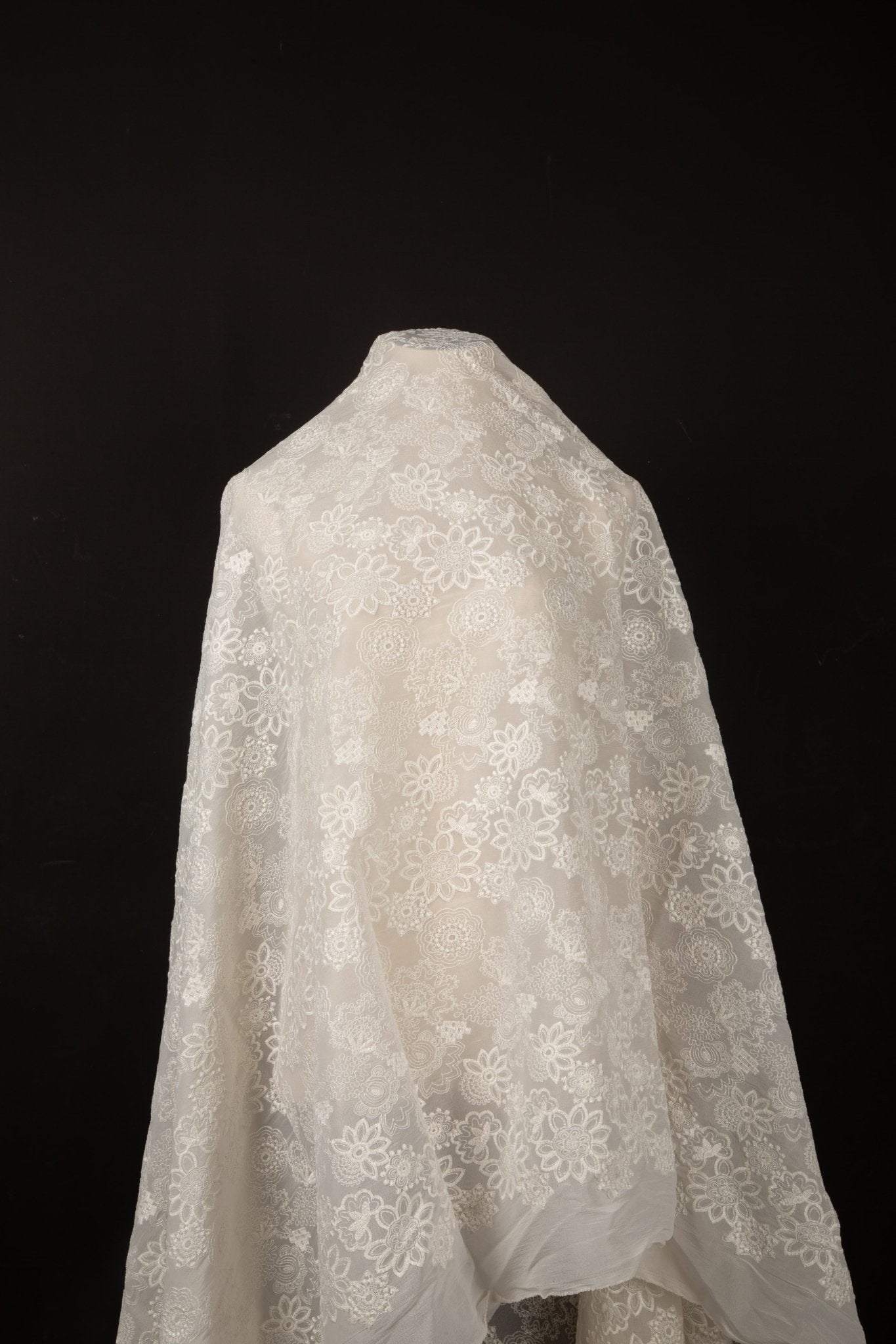 A lightweight, ivory-white flat embroidery organza fabric, with a variety of stylized, outline-floral motifs.

