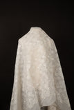 A lightweight, ivory-white flat embroidery organza fabric, with a variety of stylized, outline-floral motifs.
