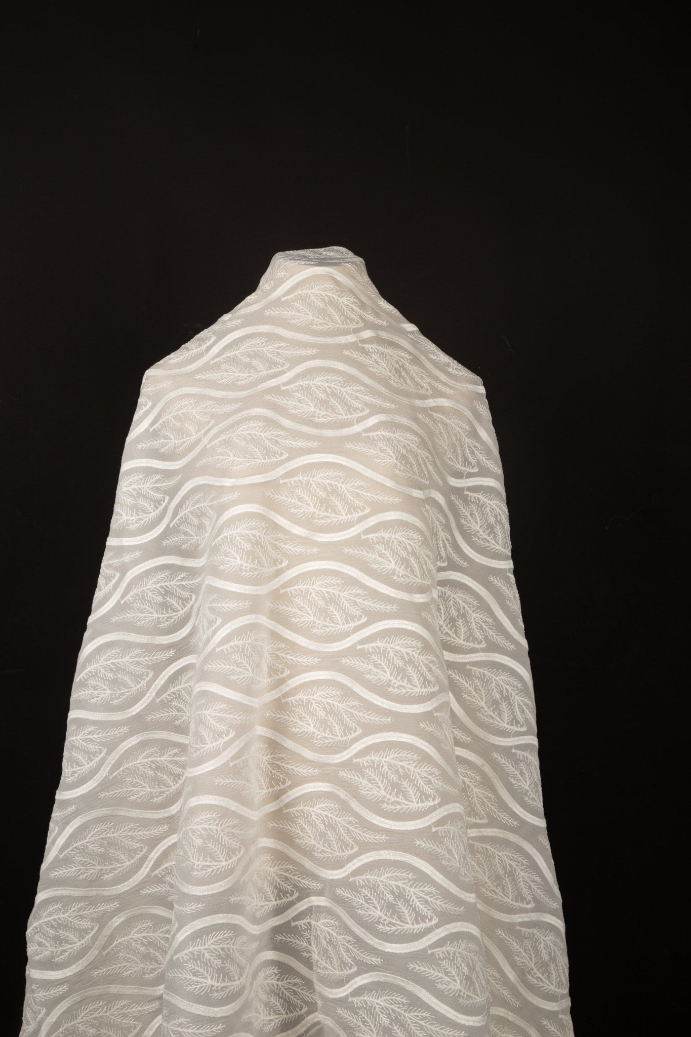An ivory-white flat embroidery organza fabric, with a horizontal striped pattern of wavy lines and fern-like leaves.

