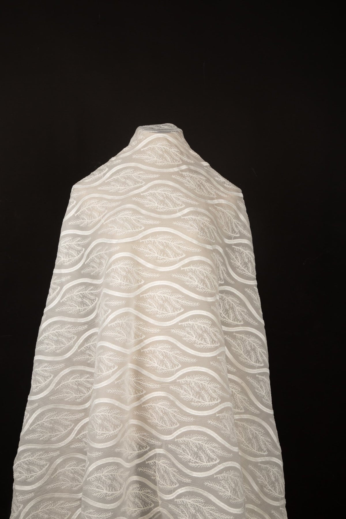 An ivory-white flat embroidery organza fabric, with a horizontal striped pattern of wavy lines and fern-like leaves.
