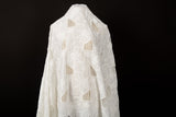 A white laser-cut embroidery fabric, with a pattern of geometric cut-out squares and white floral embroidery.