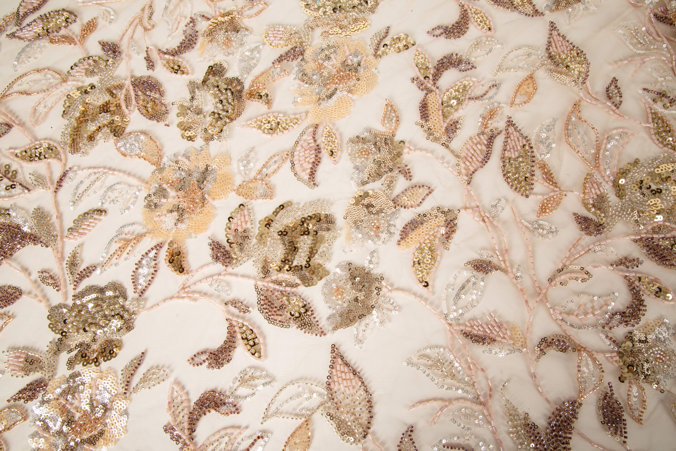lose-up of integrated sequin and glass bead floral embroidery on a delicate mesh base, demonstrating precision multi-material registration for premium apparel.