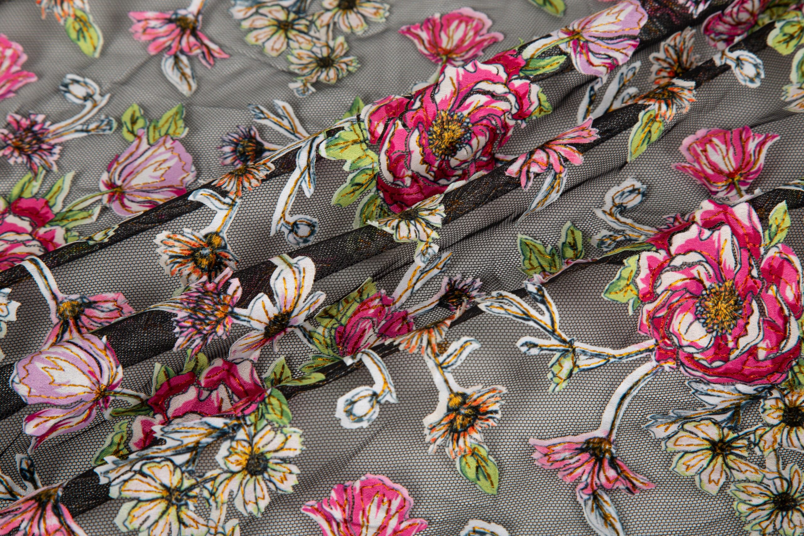 Close-up of applique embroidery showing precision-cut fabric layers stitched onto mesh, demonstrating clean edges for high-end garments.