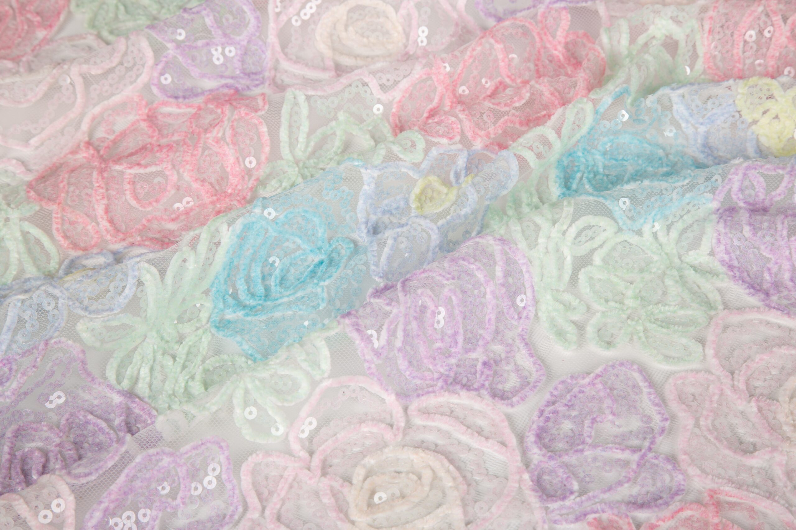 Close-up of 3D rope embroidery on sheer mesh, featuring pastel-colored floral patterns with small integrated sequins for a textured, high-end look.